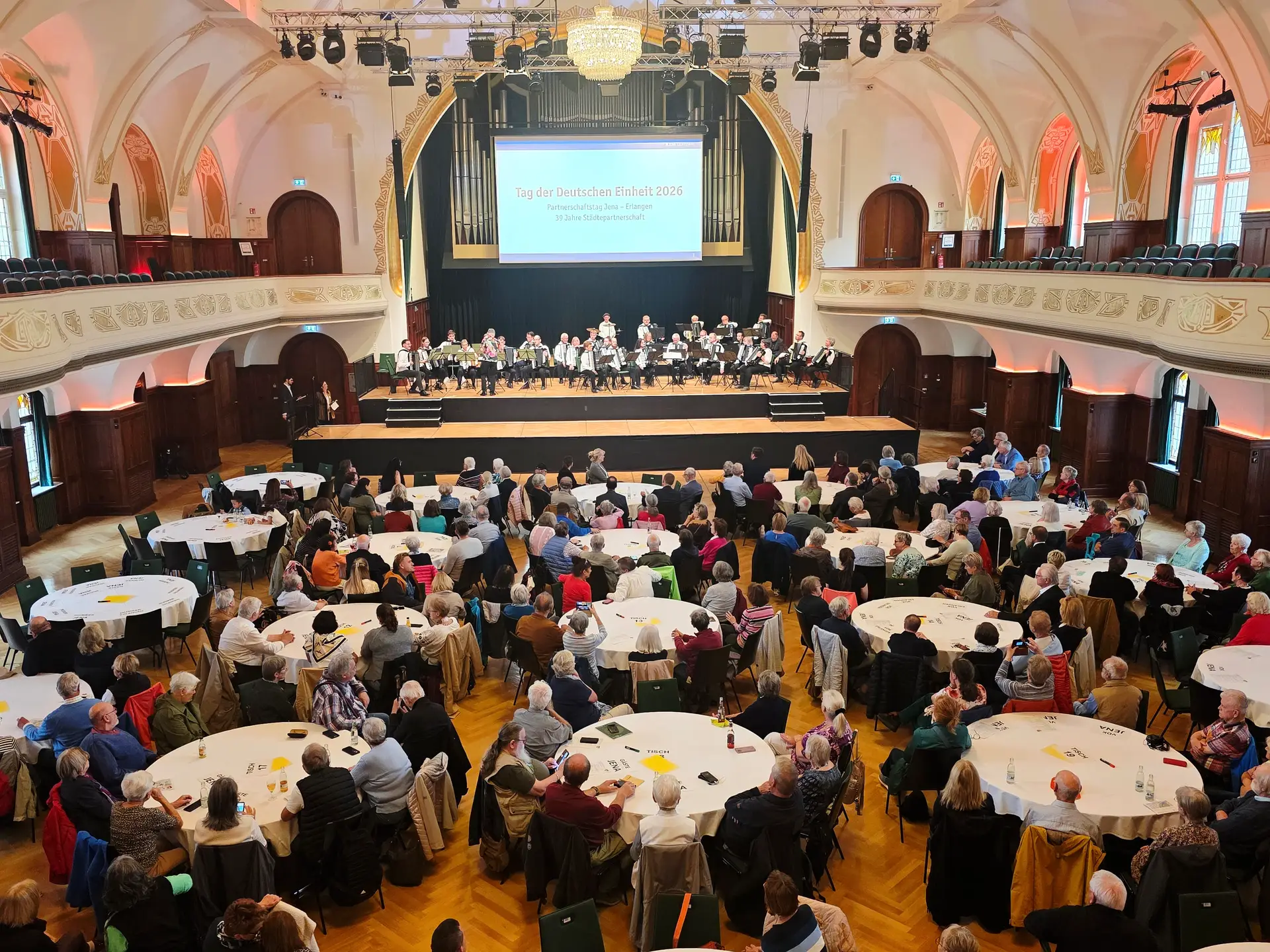 Personen sitzen in einem Saal und nehmen an einem Festakt im Volkshaus teil.